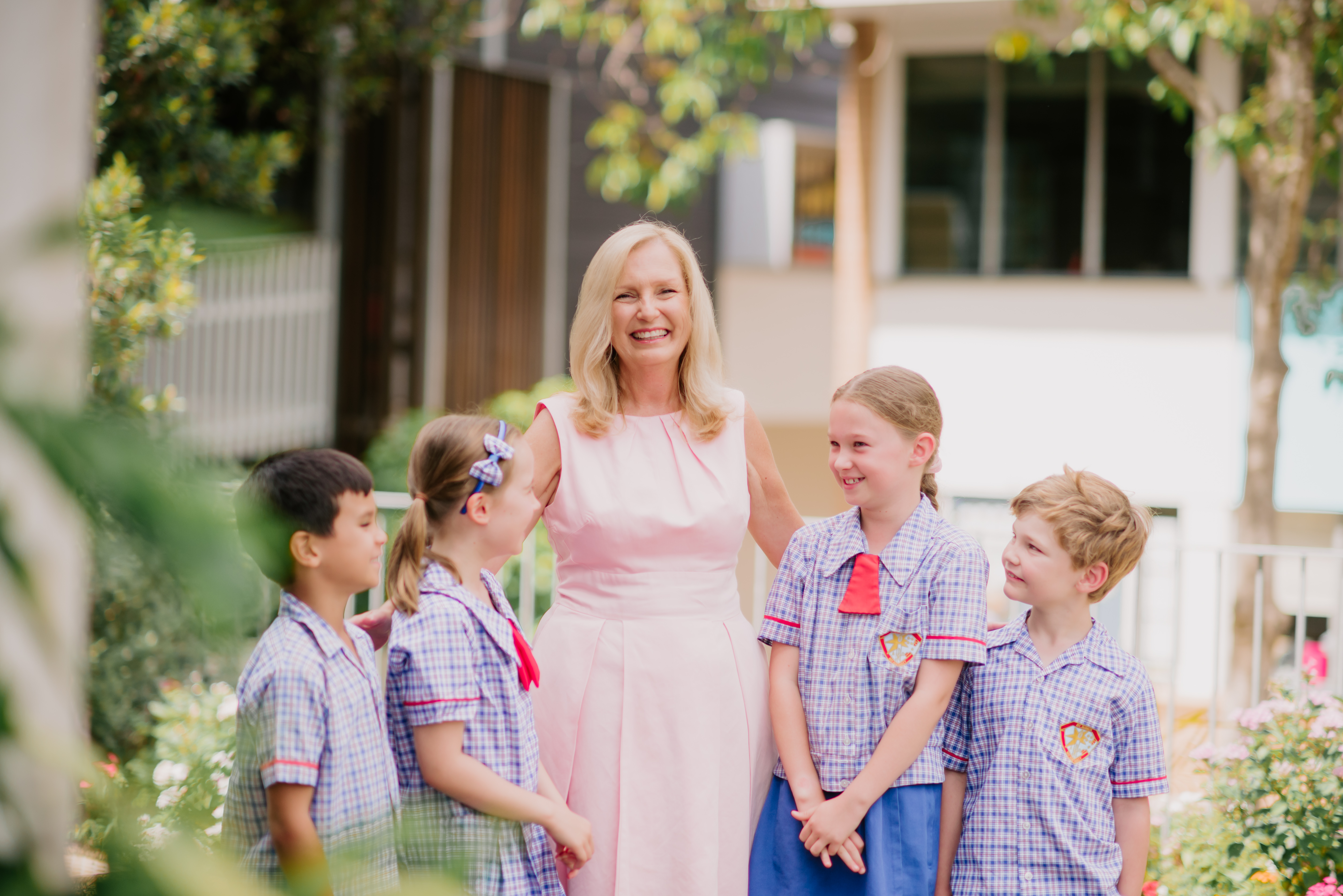 Adult and students standing together outdoors on school grounds.